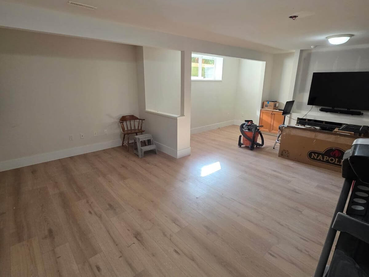 Basement renovation in Langley by TILEMART with new light oak luxury vinyl plank flooring, bright walls, and a refreshed modern look.