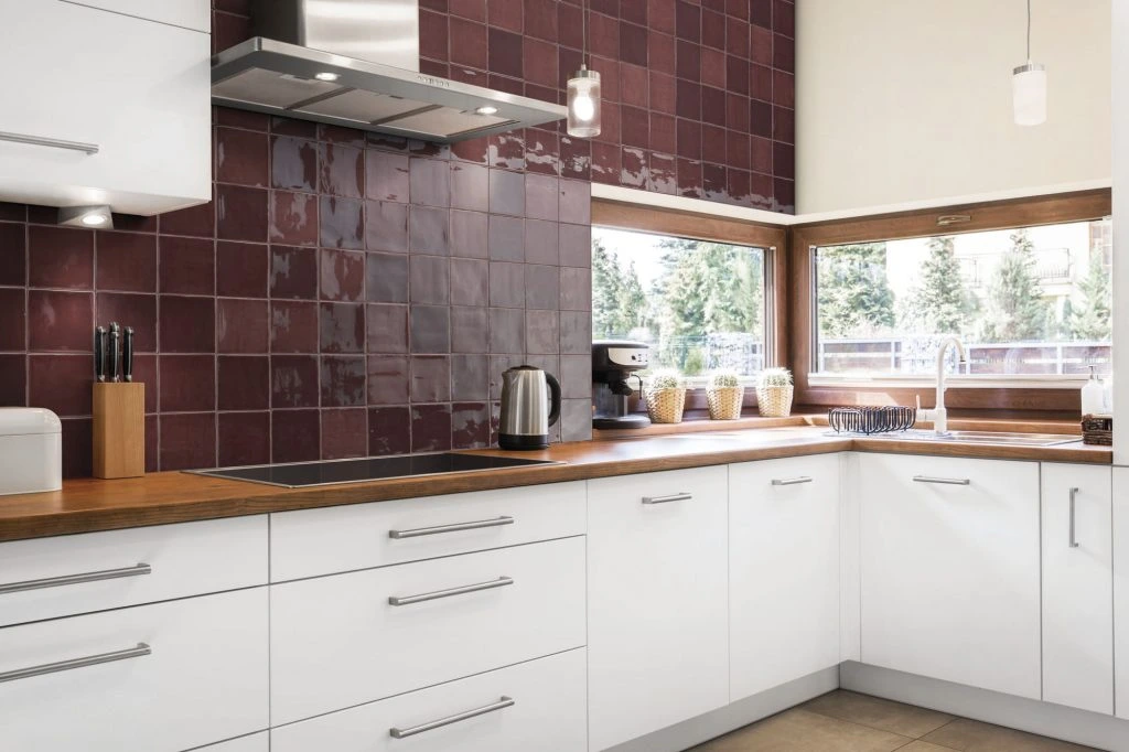 Glossy burgundy Zellige tile kitchen backsplash in a modern white kitchen