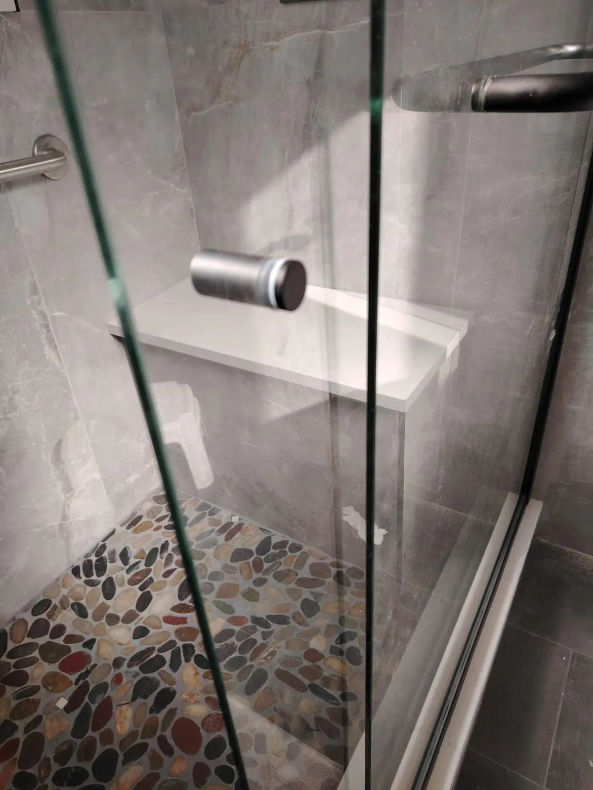 Custom walk-in shower with built-in bench and pebble tile floor in Kerrisdale Vancouver